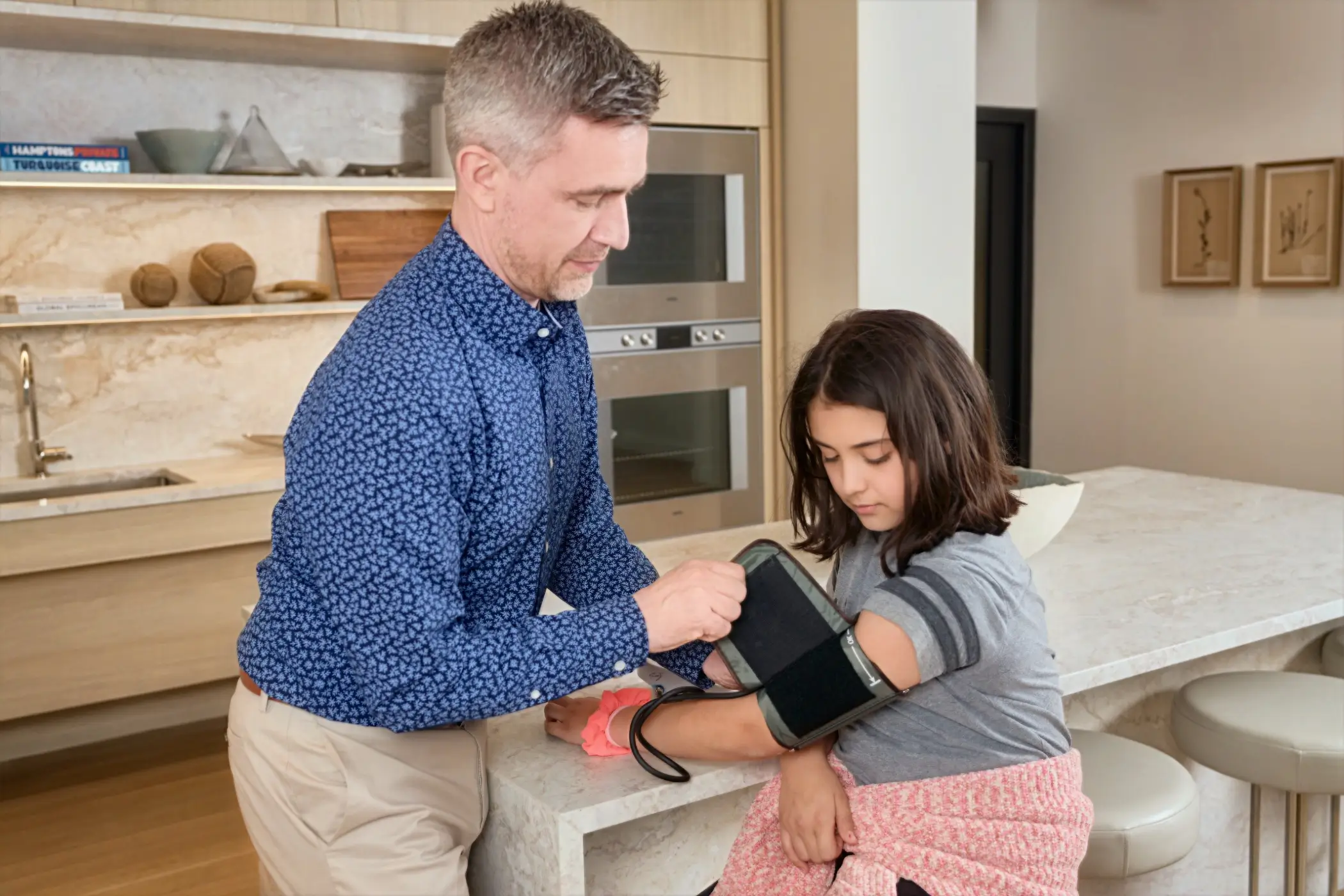 Pediatrician putting on blood pressure cuff of 10 year old girl in kitchen