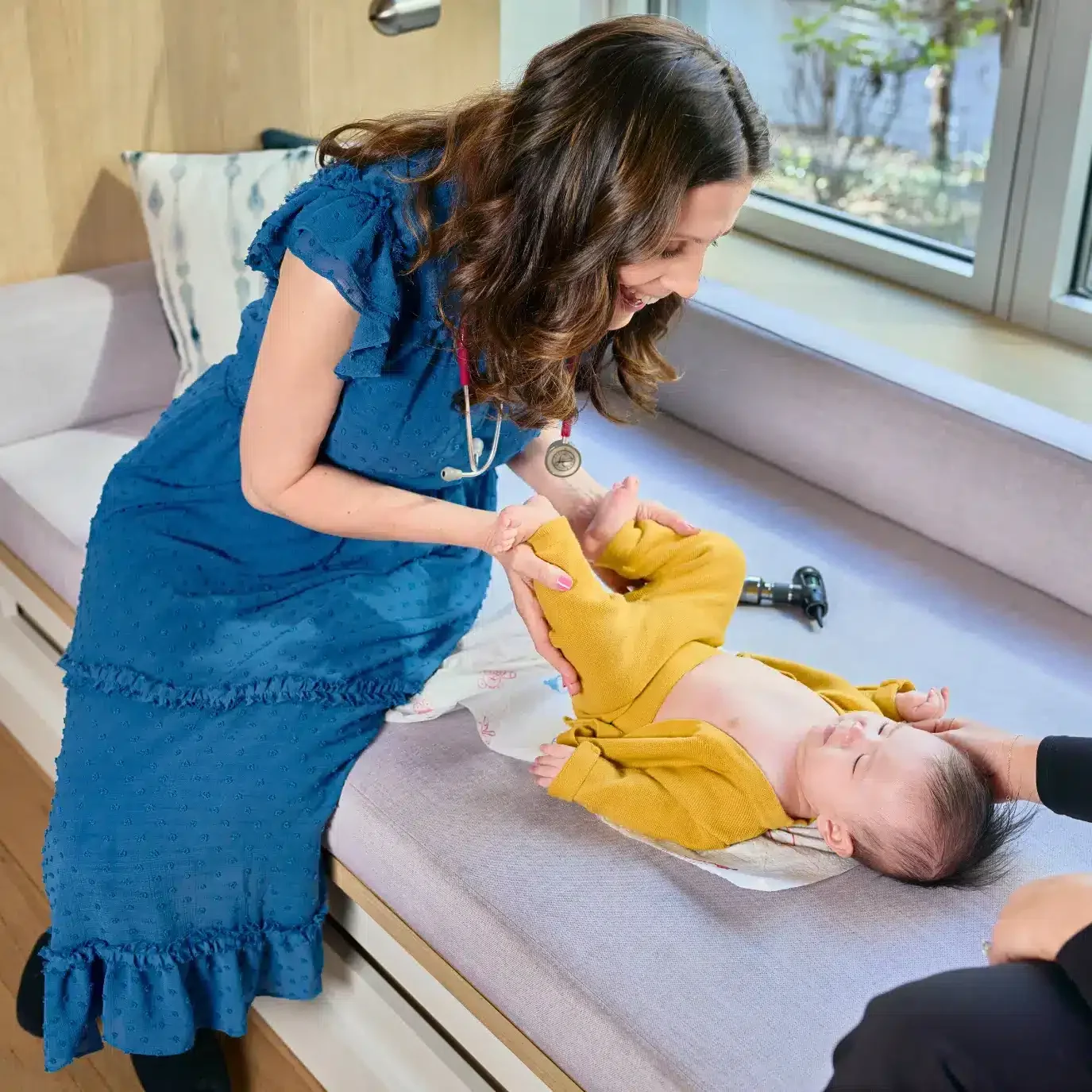 Female Pediatrician smiling at baby during at home newborn well exam